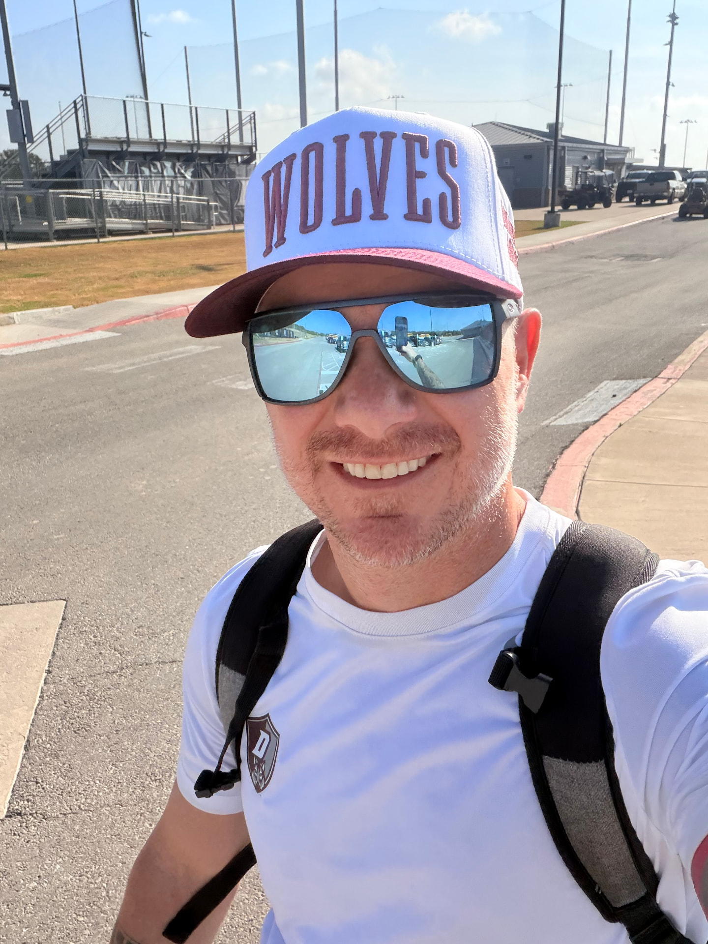 Tristan Richards, founder of YearWorks, wearing a WOLVES hat and sunglasses at a school athletic complex.